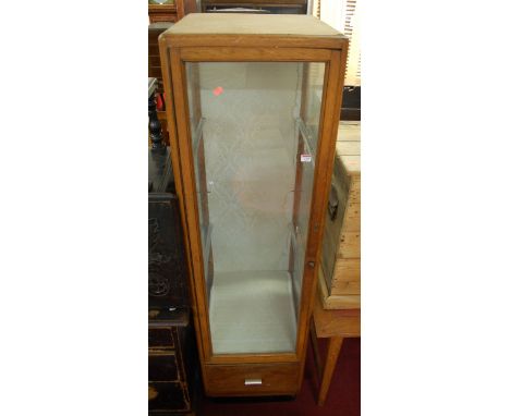 An Art Deco oak single door glazed shop display cabinet, having twin interior shelves and single long lower drawer, width 50c