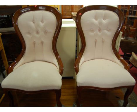 A pair of reproduction mahogany and button back upholstered spoonback nursing chairs