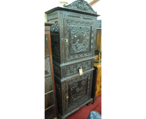 An early 20th century Continental stained and heavily relief carved oak side cupboard, having upper and lower cupboard door d