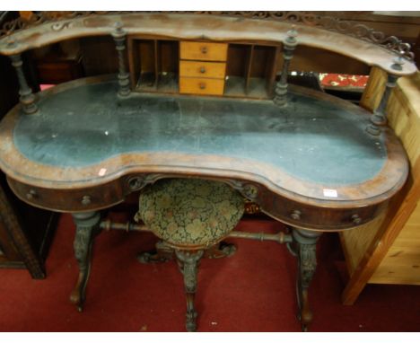 A mid-Victorian figured walnut kidney shaped writing table, having a fret carved raised superstructure over rexine inset surf