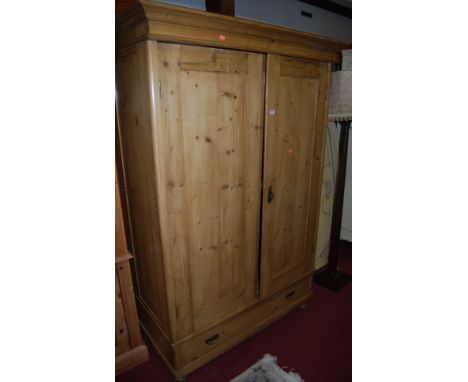 A reclaimed pine double door wardrobe, having single long lower drawer, raised on squat bun supports, w.124cm