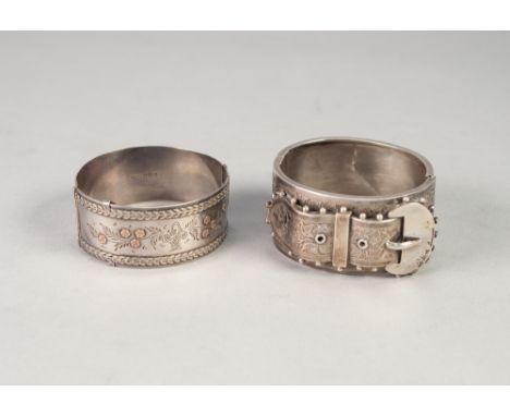 VICTORIAN SILVER BROAD HINGE OPENING BANGLE, the engraved top having applied strap and buckle decoration in free relief, 1 1/