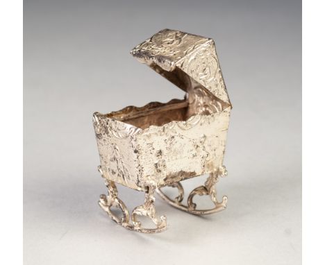 LATE NINETEENTH CENTURY CONTINENTAL SILVER MINIATURE CRIB with hood and lateral rockers, the whole repousse with putti in lan