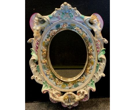 A Capodimonte rococo style ceramic mirror, decorated with naked ladies, cherubs, swirls and scrolls, 65x42cm 