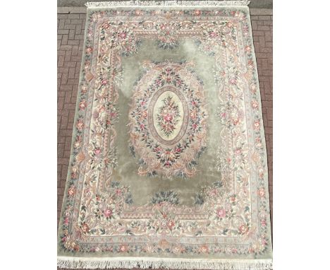 A large Chinese woollen rug, with sculpted flower and foliage decoration, in tones of jade green, pink, and cream, 380cm x 27