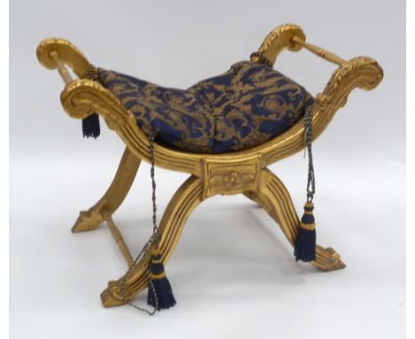 MODERN GILTWOOD X FRAMED STOOL WITH HOLLOWED OBLONG PADDED SEAT and matching cushion tied on with tassel ended cords. Height 