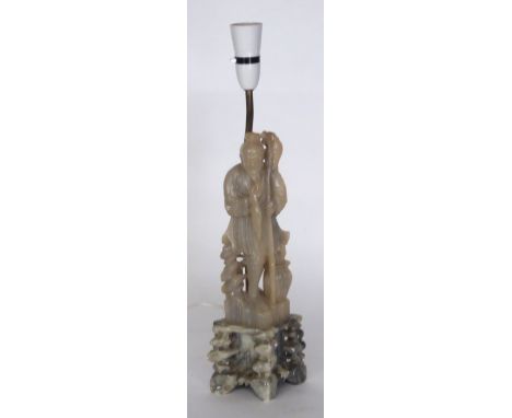 CHINESE CARVED SOAPSTONE FIGURAL TABLE LAMP, modelled as a fisherman standing on a rocky outcrop, 19 1/2" (49.5cm) high overa