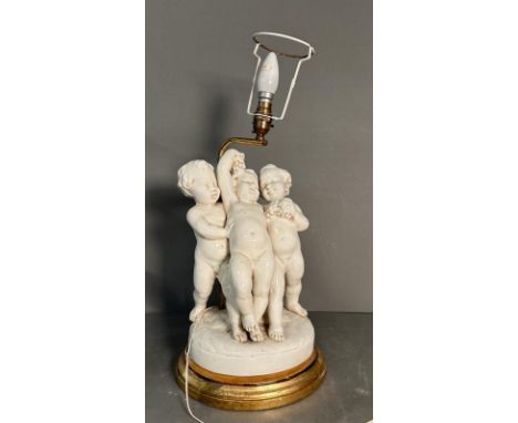 A white ceramic figural cherub table lamp on gold painted base
