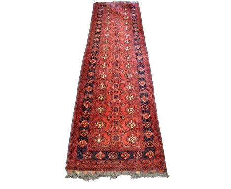 Persian style woollen red ground runner rug. Multiple geometric borders with a central rectangular medallion of stylized moti