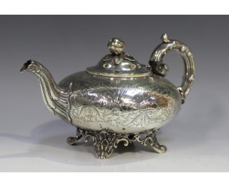 An early Victorian silver teapot with apple and leaf finial, the body squat circular engraved with birds amongst scrolling fo