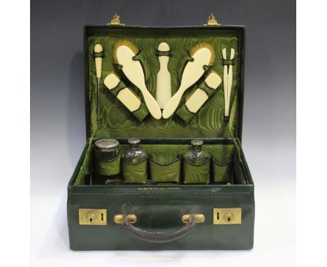 An Edwardian green leather vanity case, length 38cm, part fitted with four silver topped cut glass jars and a silver cover, e