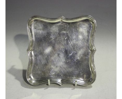 A George V silver card salver of shaped square form, raised on angular reeded legs, London 1933 by William Comyns &amp; Sons 