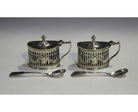 A pair of Edwardian silver oval mustards, each with hinged lid and urn shaped finial above pierced and engraved sides with fl