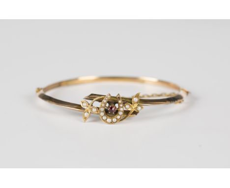 A gold, seed pearl, imitation seed pearl and garnet oval hinged bangle, the front with a horseshoe and foliate twistover moti
