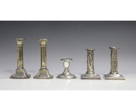 A pair of Edwardian silver candlesticks, each of cylindrical form, decorated in relief with spiralling bands of acorn and oak