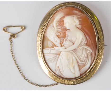 A gold mounted oval shell cameo brooch, carved as a figure of Hebe feeding the eagle within a ropetwist and foliate engraved 