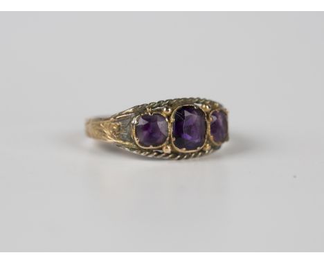 A Victorian 15ct gold and amethyst three stone ring, decorated with ropetwist sides and scroll engraved shoulders, Birmingham