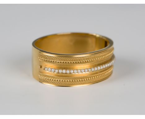 A Victorian gold and half-pearl set oval hinged bangle in the classical taste, the front mounted with a central row of half-p