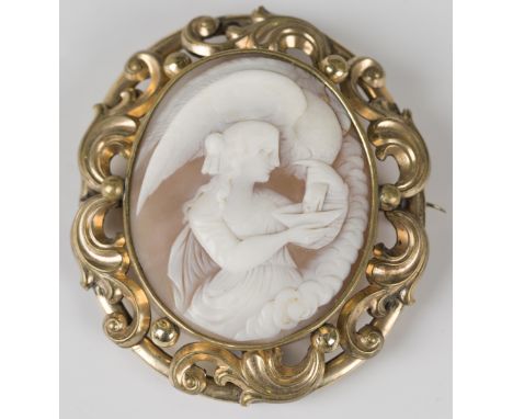 A Victorian gilt metal mounted oval shell cameo brooch, carved as Hebe feeding the eagle within a scroll pierced and beaded s