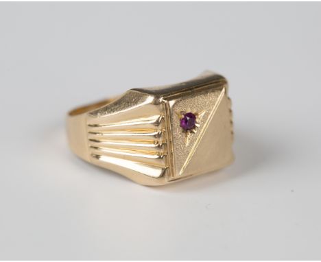 A gold and synthetic ruby square signet style ring with a partially textured finish between ridged shoulders, detailed '750',