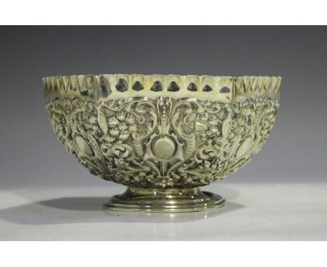A late Victorian silver hexagonal rose bowl, decorated in relief with floral and scroll decoration beneath a pinched rim, on 
