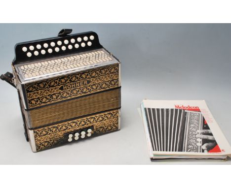 Musical Instruments: An early 20th century cased Hohner squeeze box accordion with gilded bellows, black and gilt decoration 