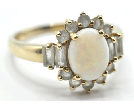 A 9ct gold opal dress ring set with a central oval opal cobochon surrounded by round and rectangular cut white stones. Assay 