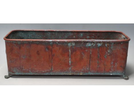 An antique 20th century copper planter / trough of rectangular form having a lipped edge and a lions head handle to each end 