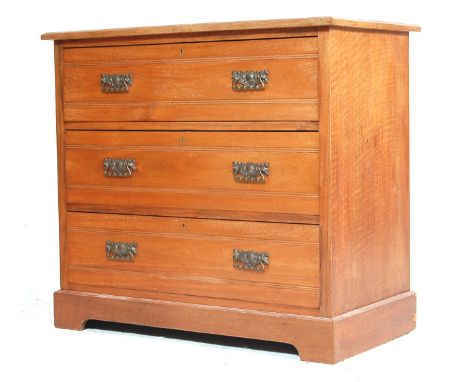 An early 20th century Edwardian arts and crafts walnut chest of drawers. The chest having a flared top over a bank of three s
