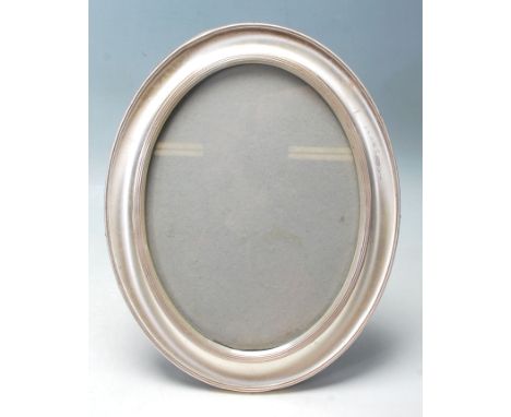 A vintage 1970’s Harrods silver hallmarked free standing oval photo frame with concave decoration to margin and wooden effect