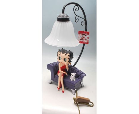 A vintage style contemporary Betty Boop table lamp / desk light of Betty Boop sitting on a purple sofa with a white dog next 