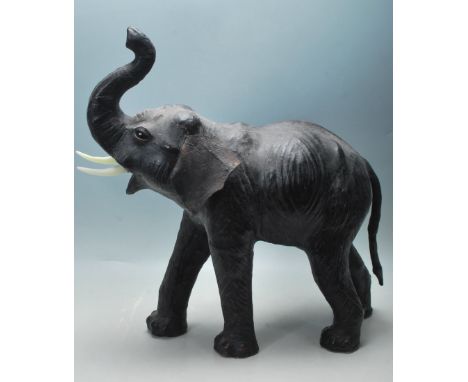 A 20th Century vintage elephant figurine of large proportions having a black leather exterior with black glass eyes, modelled