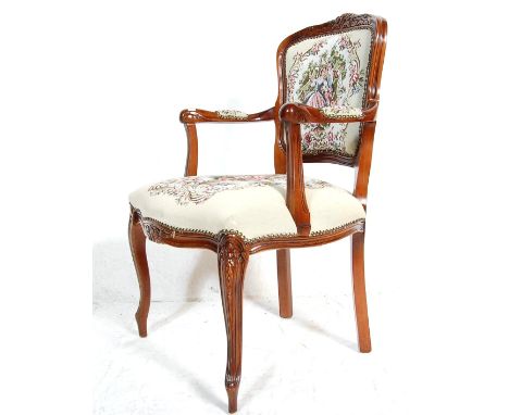 A Louis XVI style French mahogany armchair / fauteuil having a carved top rail over a cushioned tapestry back and elbow rests