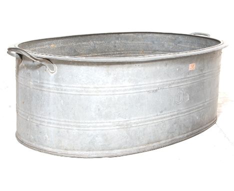 A vintage 20th century industrial galvanised metal twin handled large bath having reinforced rings around and draining plug. 