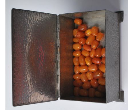 A collection of vintage butterscotch amber beads of cylindrical rounded form, each with drilled holes, all within an arts and