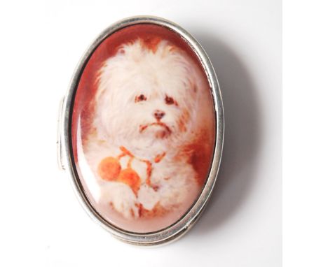 A stamped 925 silver and enamel pill pot. Atop the lid is an inlaid oval panel depicting a show dog, most likely a terrier or