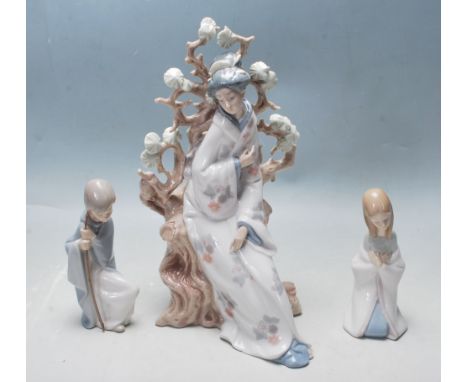 A group of three Lladro ceramic figurines to include a large geisha along with two smaller Lladro children’s ceramic figurine