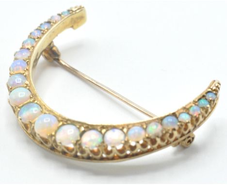 A 20th Century gold and opal brooch in the form of a crescent moon being set with round opal cabochons having a hinge pin and