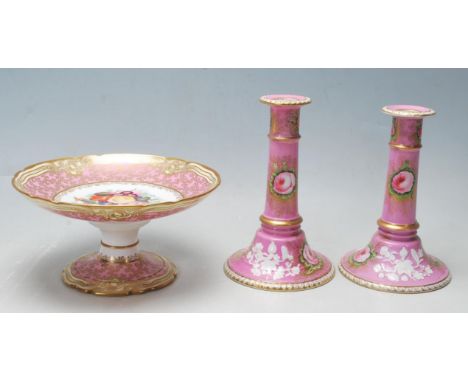 A 19th Century Victorian continental ceramic tazza and candlesticks decorated in gilt and pink with a central floral panel to