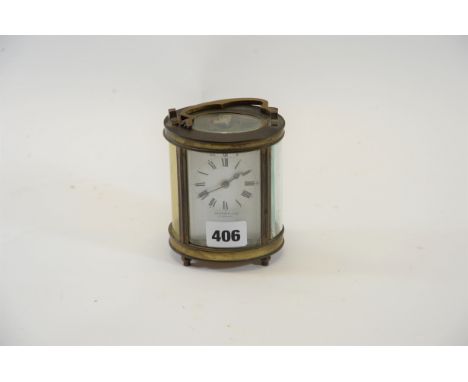 AN EARLY 20TH CENTURY OVAL BRASS 8 DAY CARRIAGE CLOCK with white enamel dial, raised on turned feet, 4 1/2 ins high (handle d