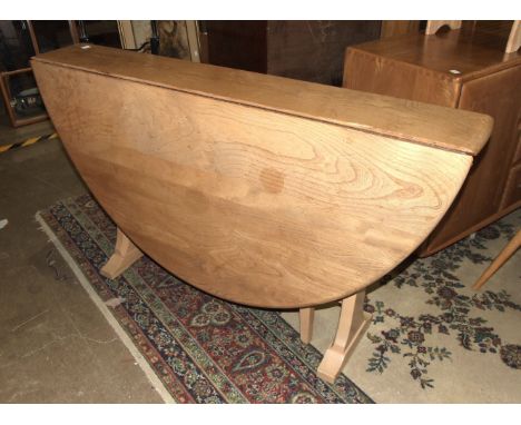 An Ercol oval drop-leaf dining table, 128cm wide, 133cm long (open) and five spindle-back chairs.