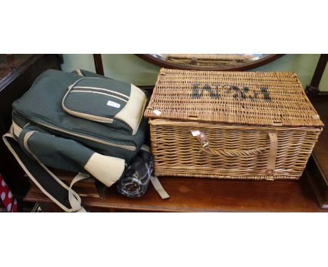 A wicker picnic hamper with drinking glasses with a picnic rucksack.