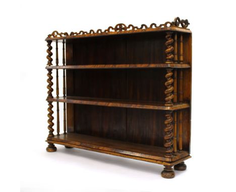 A Victorian walnut three tier open bookcase with barley twist columns, turned supports and a fretwork gallery on bun feet, w.