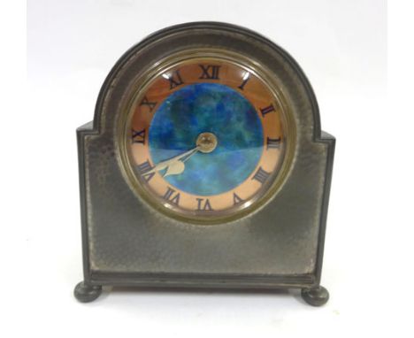 A Liberty & Co. mantle clock, the Tudric pewter hammered case of domed form with bun feet, the copper and enamelled face with