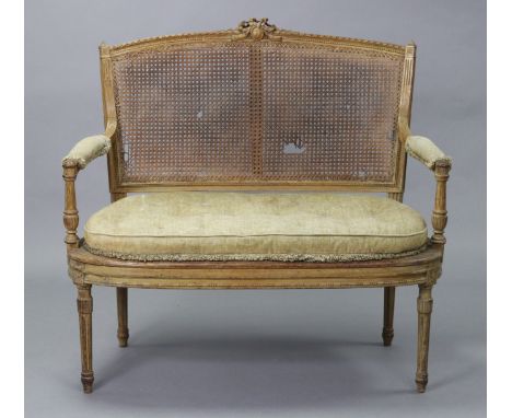 A 19th century French carved beech frame small sofa in the Louis XVI style, with curved cane-panel to the back, open arms &am