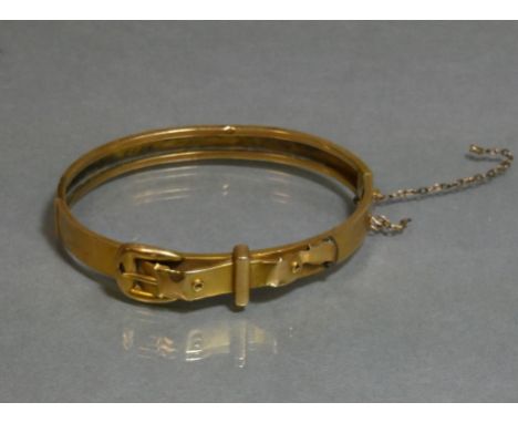 A yellow metal stiff hinged bangle of belt &amp; buckle design, marked “14” (8.8g; w.a.f.)