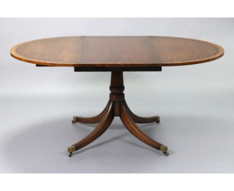 A regency-style mahogany extending dining table with crossbanded circular top, fitted two additional leaves, on ring-turned c