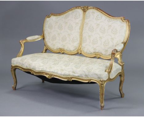 A 19th century French carved giltwood frame sofa in the Louis XVI style, the shaped back, padded open arms &amp; seat upholst