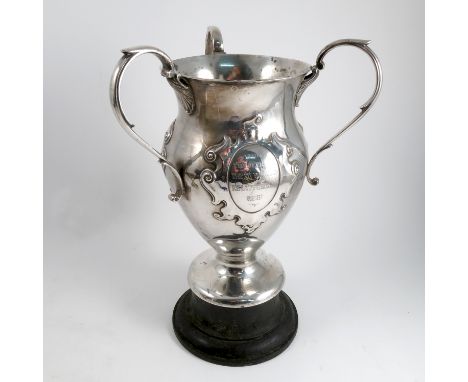 A silver three handled trophy cup, of baluster form, having three engraved oval plaques with scroll frame, engraved In Memory