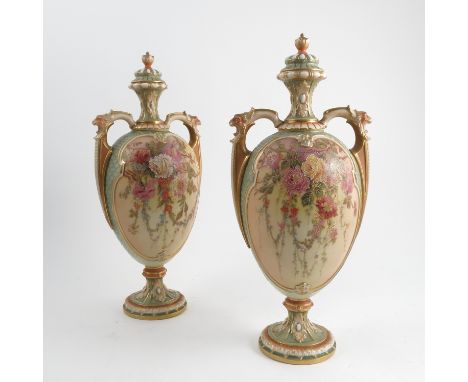 A pair of Royal Worcester covered vases, decorated with blush ivory panels with a green scale, with cascading floral panels b